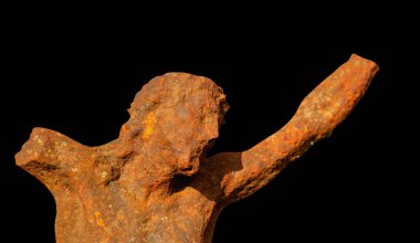 Kara arka planda İsa 'nın çarmıha gerilmesinin eski çağlardan kalma demir heykeli. Yatay resim.