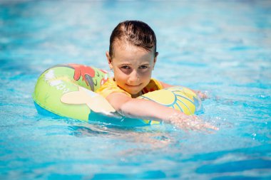 Güzel mutlu çocuk havuzda iyi eğlenceler. Şişme yüzükteki neşeli kız çocuğu. Seyahat, sağlıklı yaşam tarzı, yüzme aktiviteleri ve yaz tatili konsepti.. 