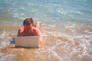 Adanın sahilinde dizüstü bilgisayarı olan bir iş adamı. Boşluğu kopyala.