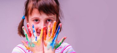 Renkli elleri mutluluk ve neşe sembolü olan mutlu küçük şirin kız çocuğunun portresi. Boşluğu kopyala.