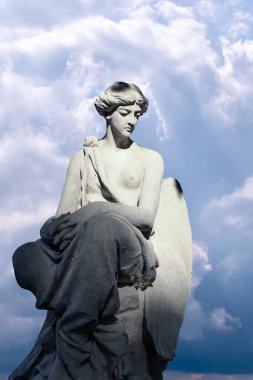 Dramatik bulutlu arka planda kanatları olan bir melek. Dikey resim.