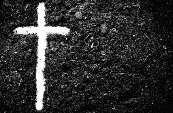 The silhouette of cross against of soil background. The cross as symbol for Jesus Christ. Christianity, religion, faith concept. Black and white horizontal image.