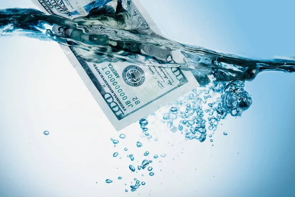 Money concept. US Dollar sinking in water as symbol of global financiall crisis.