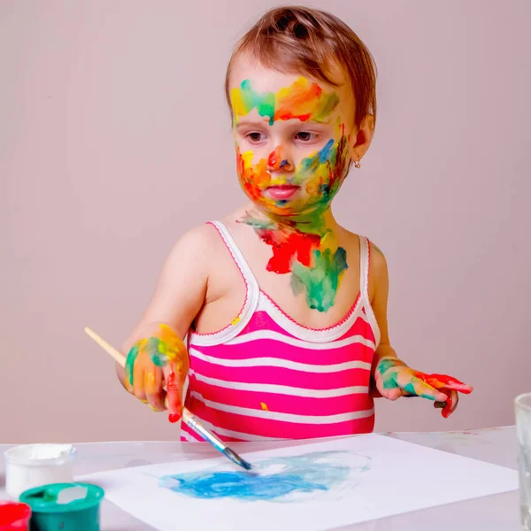 Painting lessons. Little cute girl with children\'s colorful makeup paints the picture. Art, education and childhood concept.