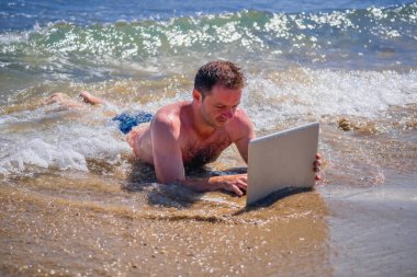 Education and work always and everywhere as the best way to be successful. Male entrepreneur working with laptop in the sea. Horizontal image.