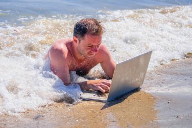 Conceptual image: education and work always and everywhere as the best way to be successful. Male entrepreneur working with laptop in the water of sea or ocean. 