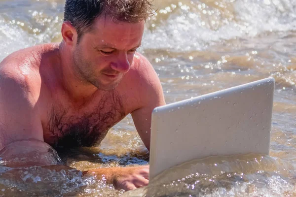 Education and work always and everywhere as the best way to be successful. Close up portrait of male entrepreneur working with laptop in the sea.