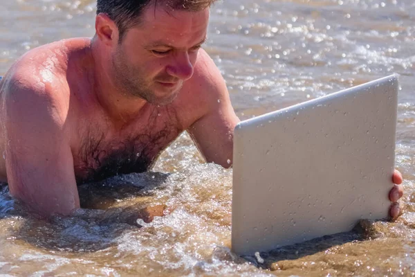 Education and work always and everywhere as the best way to be successful. Male entrepreneur working with laptop in the sea.