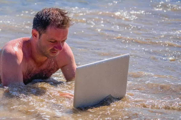 Education and work always and everywhere as the best way to be successful. Close up portrait of male entrepreneur working with laptop in the sea. Copy space.