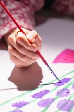  Çocuğun eli boya renkleri çiziyor. Elimizdeki seçici odaklanma. Dikey resim.