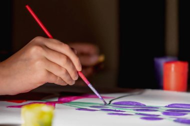  Sanat, aktif yaşam tarzı ve yaratıcılık kavramı. Suluboya resim yapmayı öğrenen genç bir kızın portresi yok. Renkli fırçalar kullanarak evde çizim yapıyor. Eldeki seçici odaklanma.