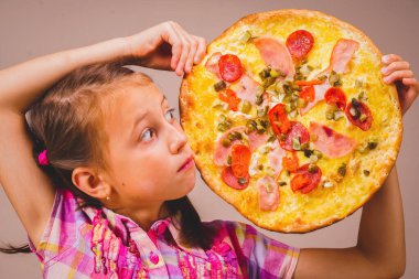 Fast food ve pizzacı kavramı. Lezzetli, büyük bir dilim pizzayı yemeye hazır tutan güzel bir kızın komik portresi. Yatay resim.