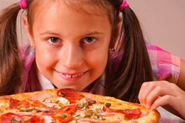 Çocuk pizzası. Elinde pizza tutan mutlu ve güzel bir kızın portresi. Yatay resim.