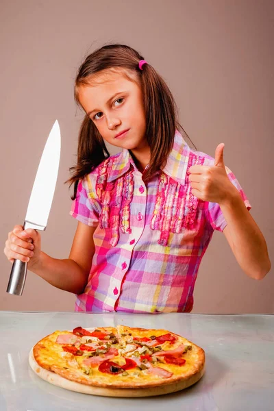 Фото Молодой Красивой Девушки Режет Пиццу Ножом Макает Большой Палец — стоковое фото