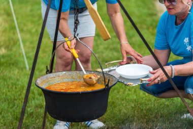 5 Haziran 2022 'de. - TEMERIN, SERBIA: Sırbistan 'ın Temerin kentinde 5 Haziran 2022' de Sırbistan 'da düzenlenen Pasuljijada Bean Festivali 2022 Gıda ve Müzik Festivali Sahneleri. İnsanlar güzel bir yaz gününün tadını çıkarırken, geleneksel yemek ve içecekler DJ ve müzik B