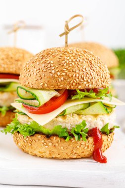 Kızarmış tavuklu hamburger, salatalık, domates, peynir ve marul..