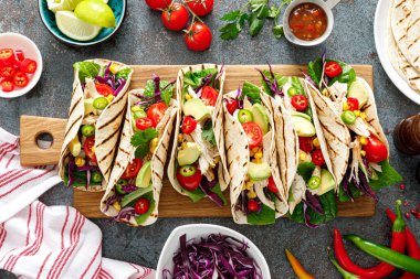 Izgara et, avokado, taze sebze salatası ve sos soslu tavuk tacoları.