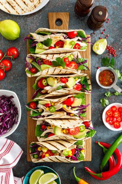 Izgara et, avokado, taze sebze salatası ve sos soslu tavuk tacoları.