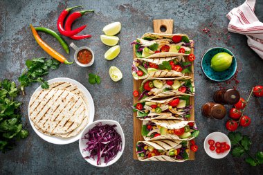 Izgara et, avokado, taze sebze salatası ve sos soslu tavuk tacoları.