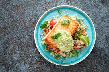 Izgara somon fileto, kinoa taze sebze salatası domates ve avokado guacamole. Üst görünüm