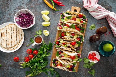 Izgara et, avokado, taze sebze salatası ve sos soslu tavuk tacoları.