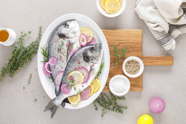 Taze dorada balığı ve pişirmek için malzemeler. Beyaz arka planda baharatları olan çiğ deniz çipurası. Sağlıklı yiyecekler, diyet. Kopyalama alanı olan üst görünüm.