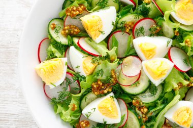 Paskalya taze sebze salatası haşlanmış yumurta, turp ve salatalık, dijon hardallı sos ve limonlu beyaz ahşap masa. Üst görünüm