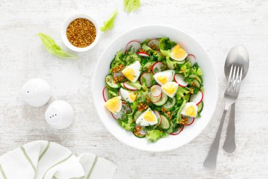 Paskalya taze sebze salatası haşlanmış yumurta, turp ve salatalık, dijon hardallı sos ve limonlu beyaz ahşap masa. Üst görünüm