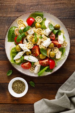 Peynirli, zeytinli, domatesli ve taze fesleğenli tavuk Caprese makarna salatası. Üst manzara, düz uzanma