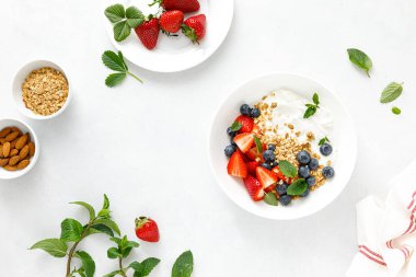 Tahıl gevreğiyle kahvaltı kasesi, sade yoğurt, çilek ve yabanmersini, üst manzara.