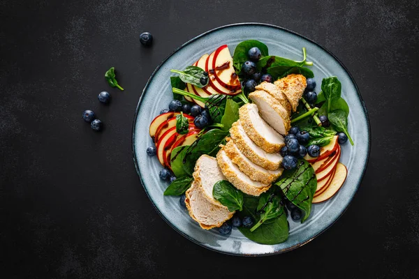 Salad with chicken meat. Fresh fruit salad with chicken breast. Meat salad with chicken fillet, spinach, apples and blueberry on plate, top view