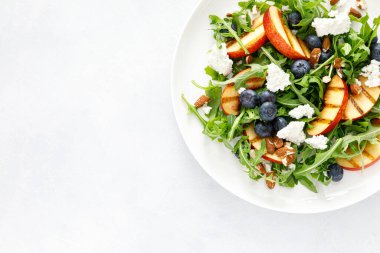 Şeftali, yabanmersini ve roka taze meyve salatası. Peynirli ve badem fıstıklı.