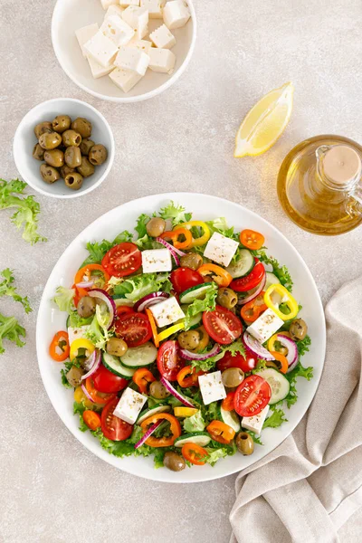 Greek salad with feta cheese, tomatoes, cucumbers, pepper, red onion and green olives. Top view