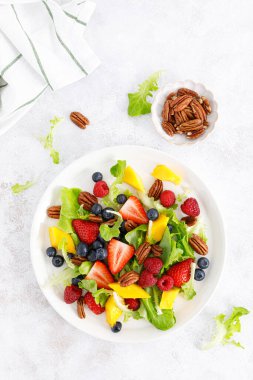 Çilekli, böğürtlenli, ahududulu, mangolu ve cevizli meyve salatası. Sağlıklı yiyecekler, diyet. Üst görünüm