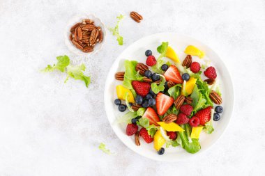 Çilekli, böğürtlenli, ahududulu, mangolu ve cevizli meyve salatası. Sağlıklı yiyecekler, diyet. Üst görünüm