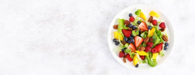 Çilekli, böğürtlenli, ahududulu, mangolu ve cevizli meyve salatası. Sağlıklı yiyecekler, diyet. Üst Manzara. Pankart