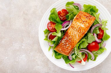 Izgara somon balığı filetosu ve domatesli taze sebze salatası, kırmızı soğan ve marul.
