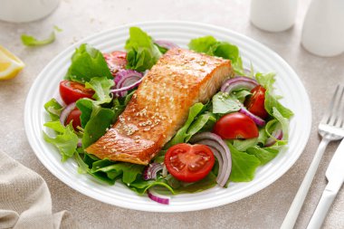 Izgara somon balığı filetosu ve domatesli taze sebze salatası, kırmızı soğan ve marul.