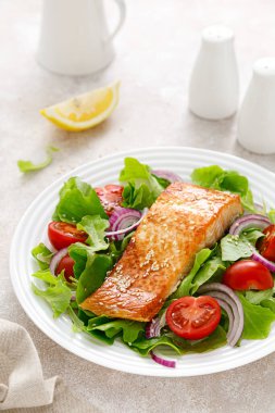 Izgara somon balığı filetosu ve domatesli taze sebze salatası, kırmızı soğan ve marul.