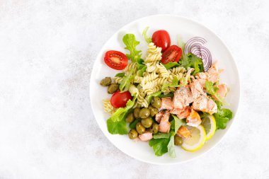 Izgara somon salatası taze marul, domates, yeşil zeytin, kırmızı soğan ve makarna. Sağlıklı yiyecekler, diyet. Üst görünüm