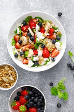 Taze çilekli meyve ve çilek salatası, yabanmersini, muz, süzme peynir ve bademli granola. Sağlıklı yemek, diyet kahvaltı.
