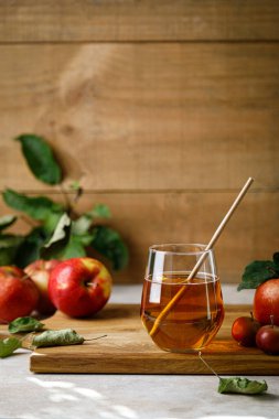 Apple juice in a glass and fresh fruits with leaves