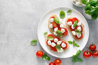 Küçük mozzarella peynirli, kiraz domatesli ve fesleğenli Caprese tostları.