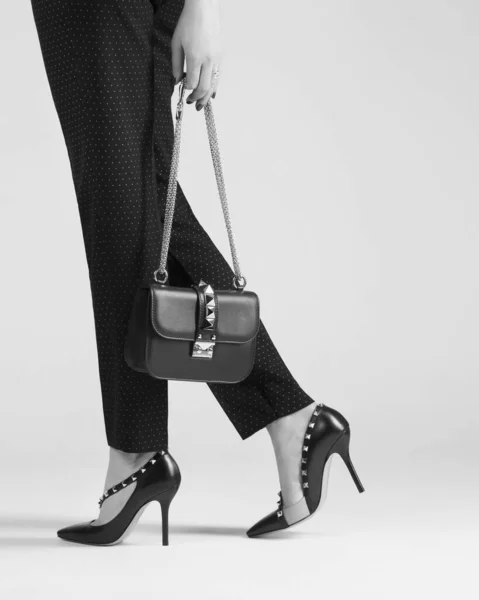 一个穿着时髦鞋子的女孩手里拿着一个包在工作室里 很时髦的样子 图库照片