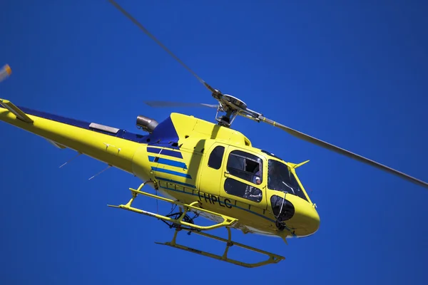 Yellow helicopter in a blue sky — Stock Photo, Image