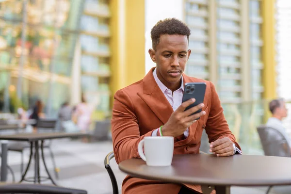 Hombre Negocios Africano Sentado Aire Libre Cafetería Con Teléfono Móvil — Foto de Stock