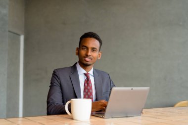 Kafede takım elbise ve kravat takan genç Afrikalı işadamının portresi.