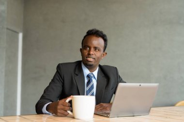 Kafede takım elbise ve kravat takan genç Afrikalı işadamının portresi.