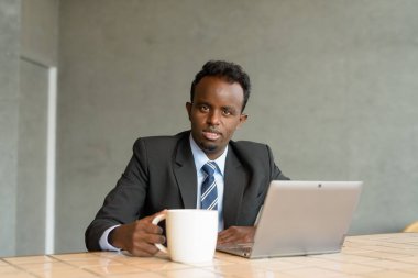 Kafede takım elbise ve kravat takan genç Afrikalı işadamının portresi.