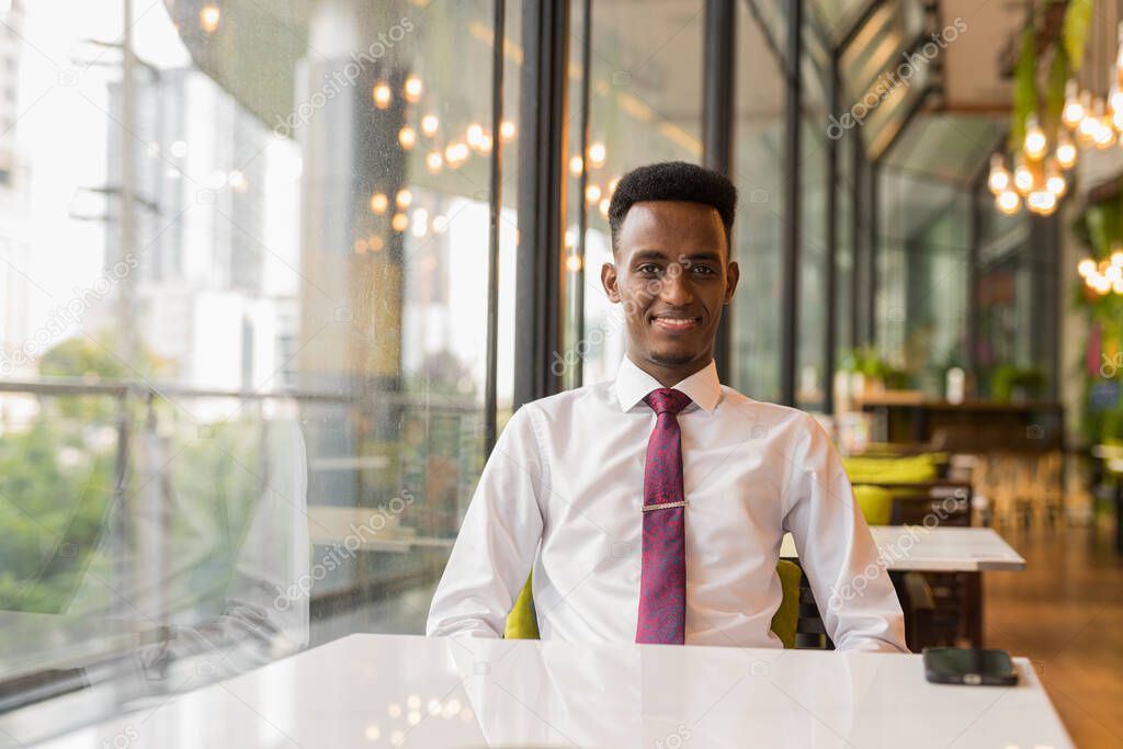 Portrait of young successful African businessman at coffee shop